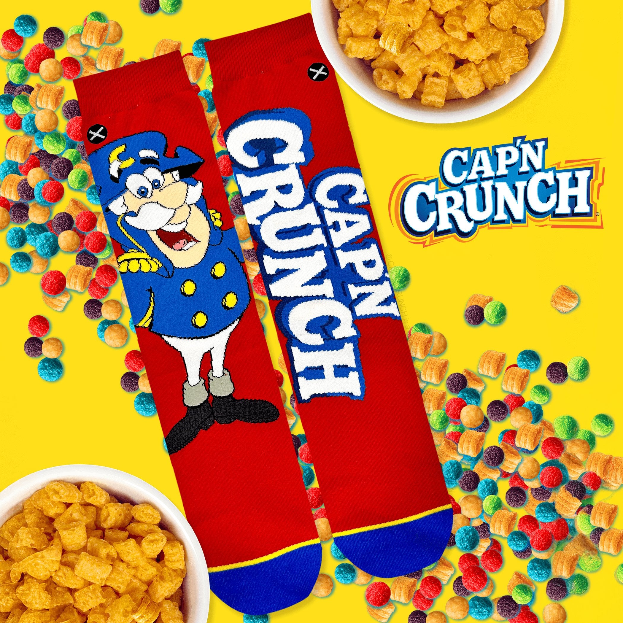 Bright yellow background with Cap’n Crunch socks featuring the iconic cereal mascot on a red background, surrounded by colorful cereal pieces.