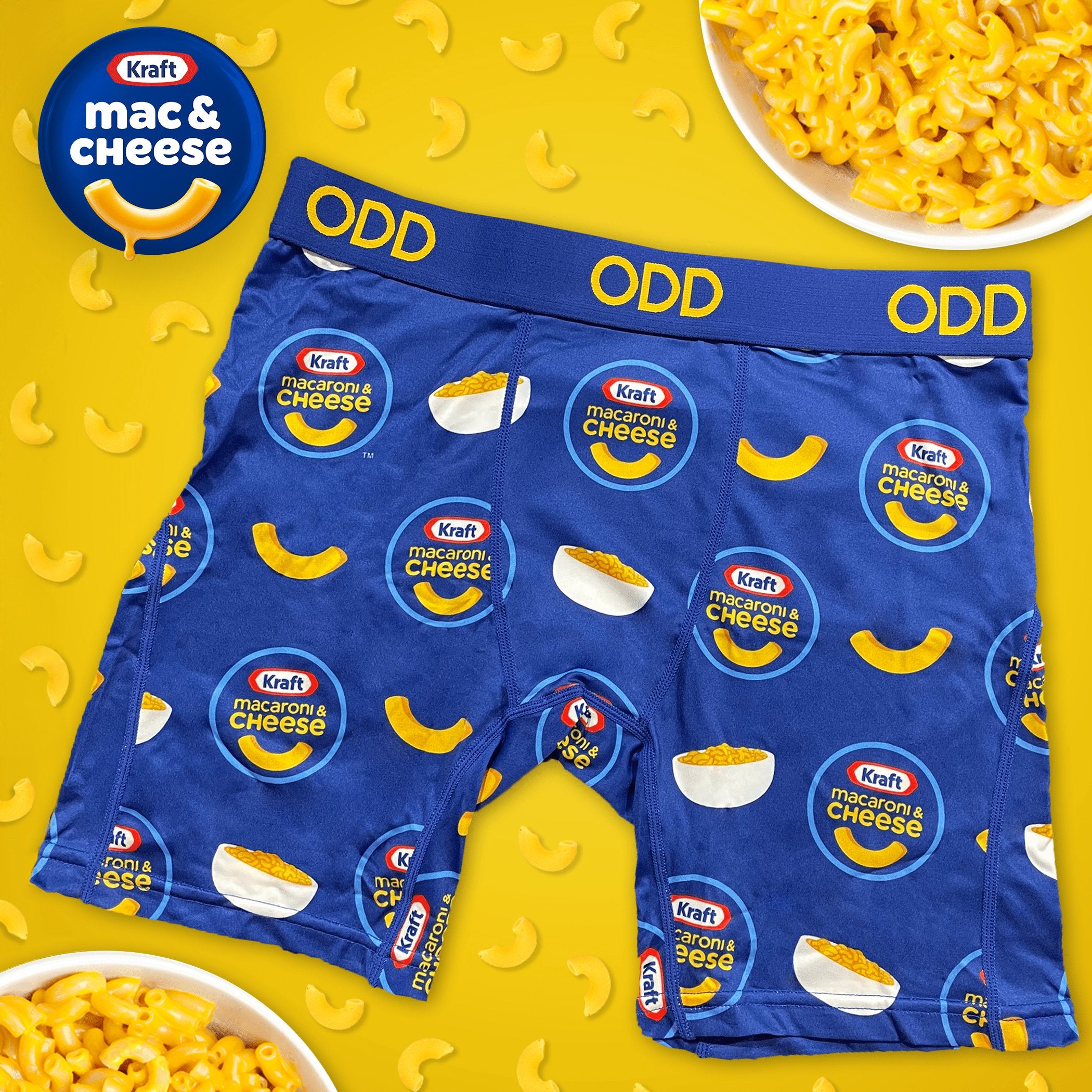 Blue boxer briefs with Kraft Mac & Cheese logos and macaroni illustrations. The waistband is yellow with "ODD" branding.