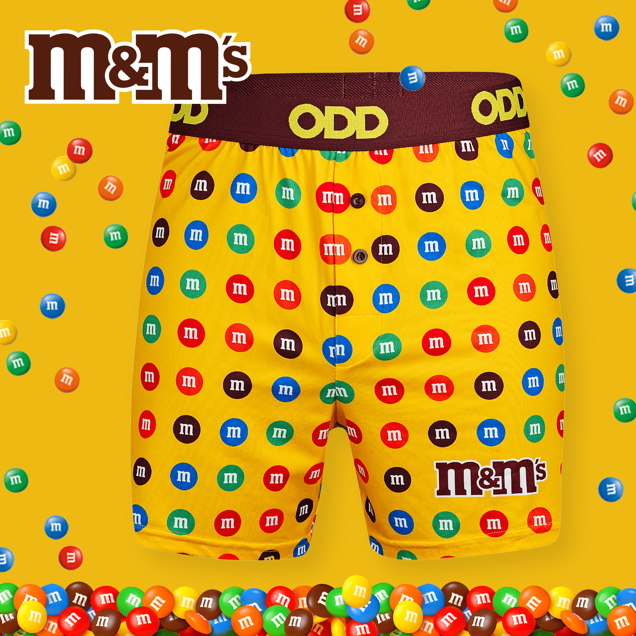 Bright yellow boxer briefs covered with colorful M&M's candy logos. The waistband features "ODD" in brown, with a large M&M's logo at the bottom.