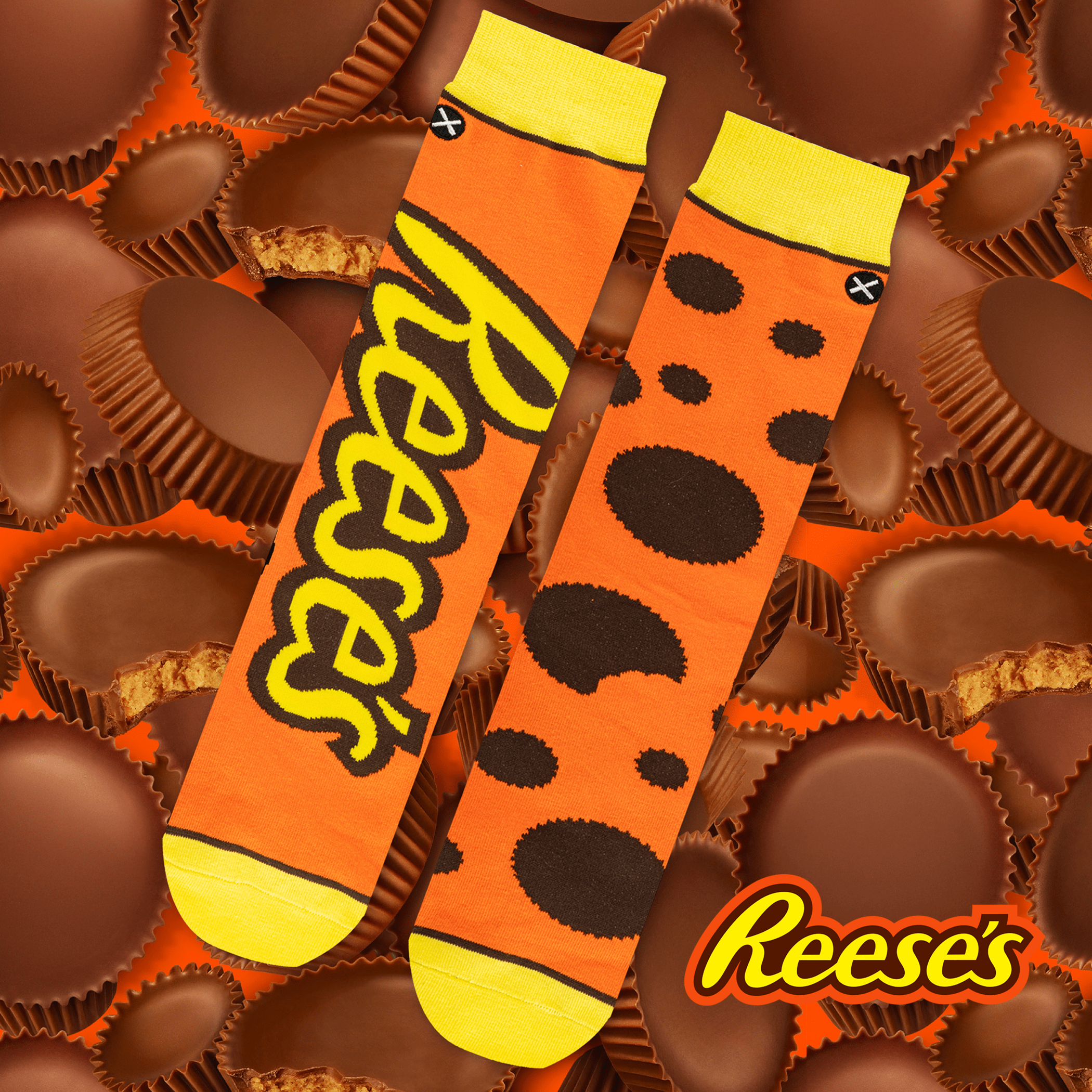 Delicious chocolatey background with Reese’s socks in orange and brown, adorned with polka dots inspired by peanut butter cups, representing the beloved candy.