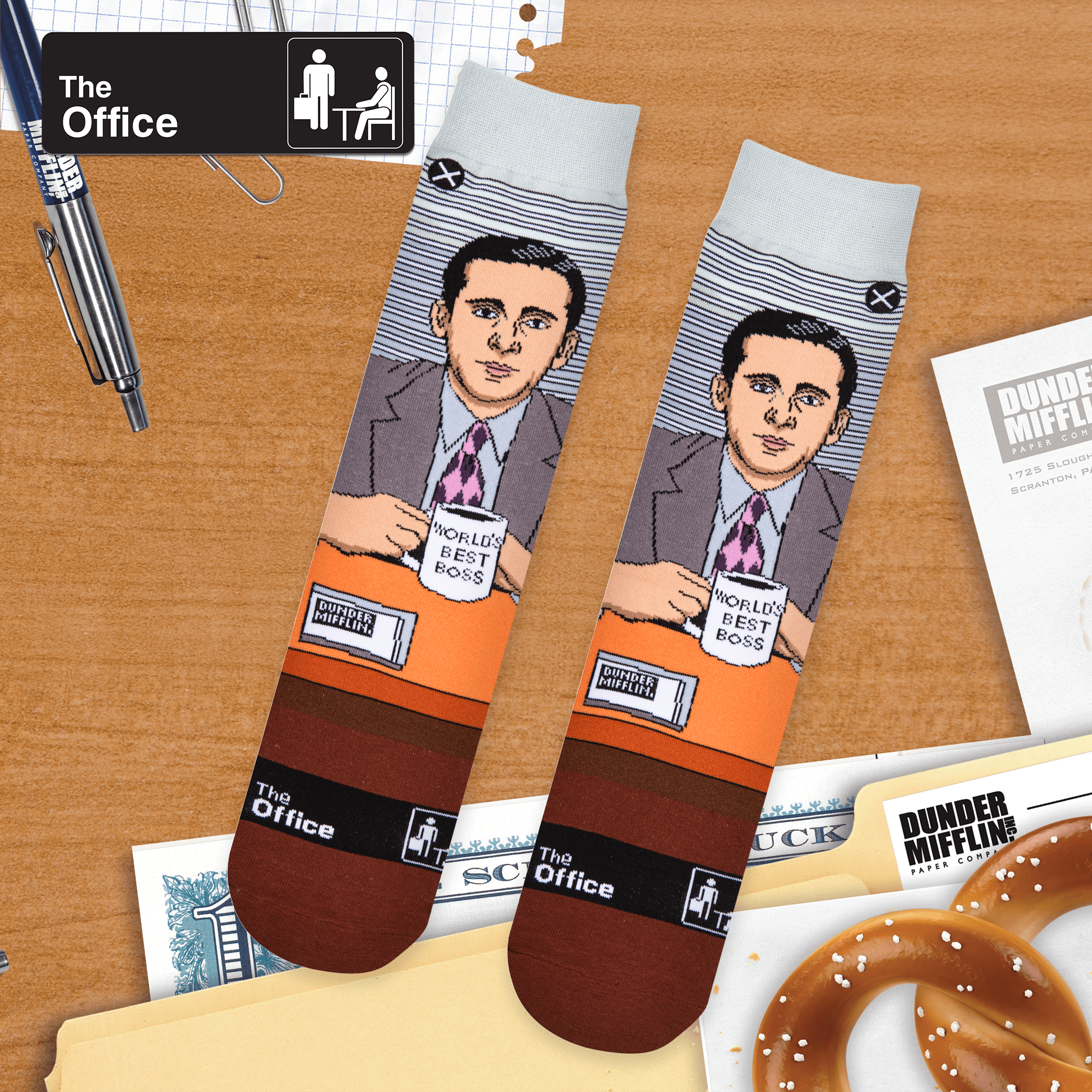 Socks featuring a cartoon-style Michael Scott holding a "World's Best Boss" mug, set against a desk and office backdrop.