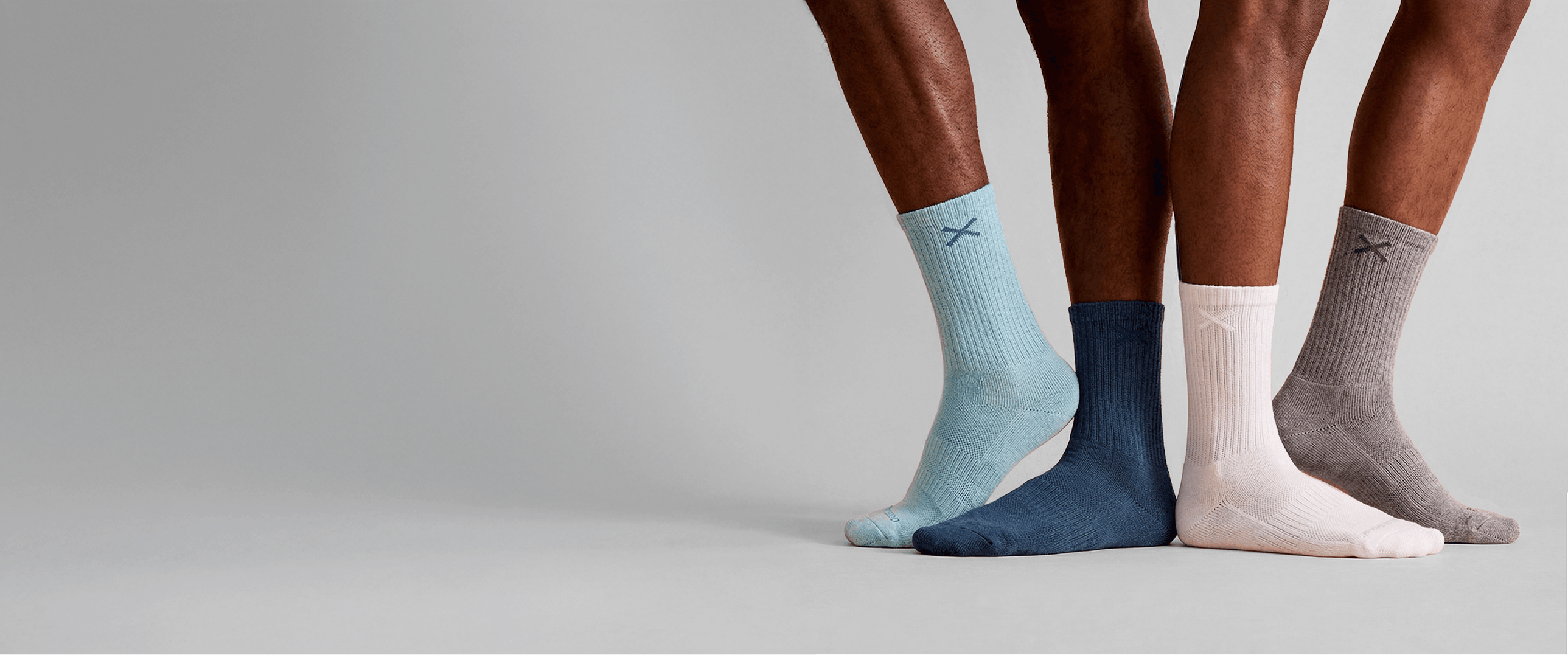 Three pairs of socks in light blue, navy, and beige on a neutral background