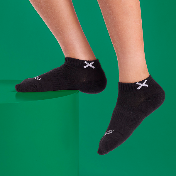 Holiday-themed image showing a child wearing black ankle socks on a festive green background.