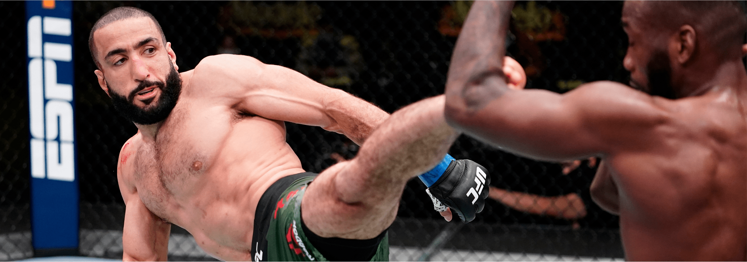 Belal Muhammad delivers a powerful kick to his opponent during a UFC fight, mid-action in the Octagon.