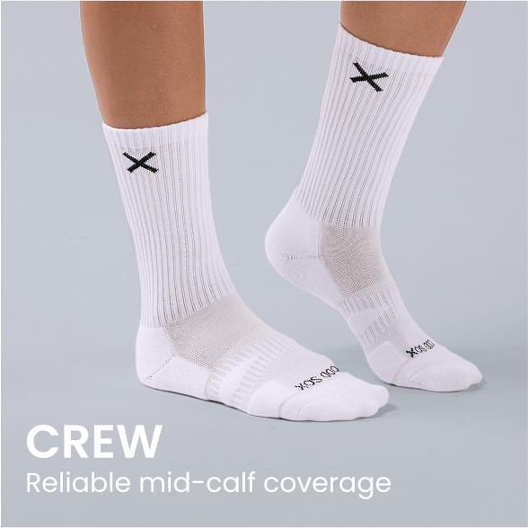White crew socks with black X logo, providing mid-calf coverage on model feet.