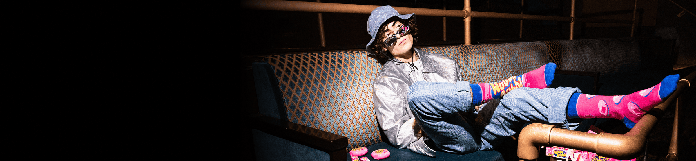 Person sitting on a couch wearing colorful socks in a dimly lit room.