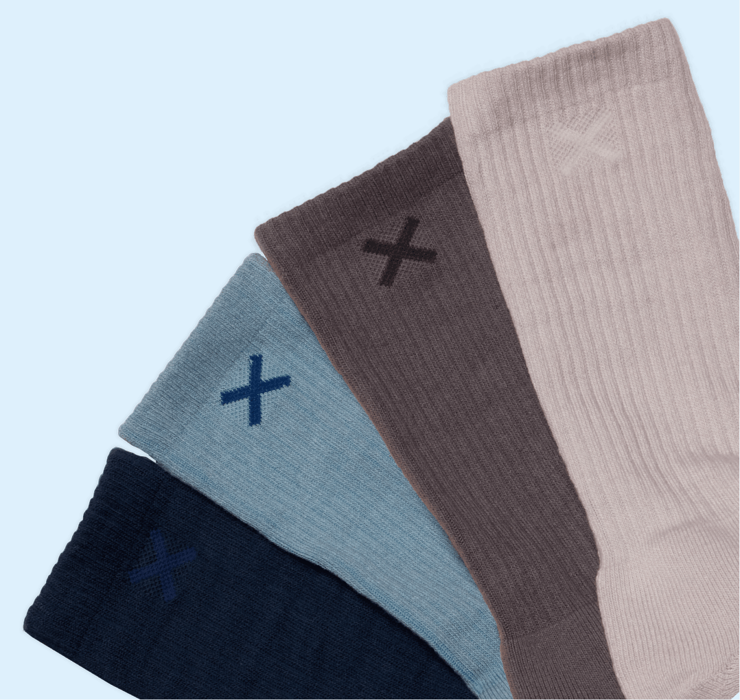 Four pairs of socks in black, blue, brown, and beige with a cross symbol on a light blue background.