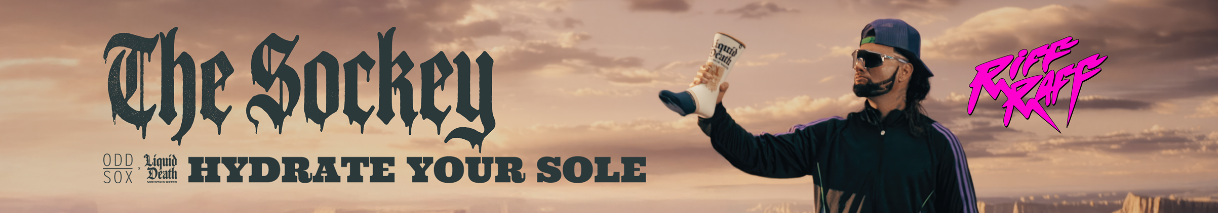 Man holding a cup with 'The Sockey' branding against a desert landscape.