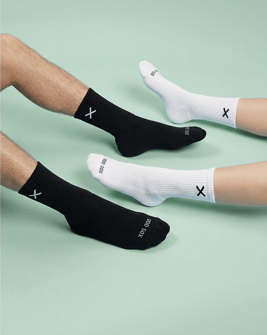 Two pairs of black and white socks with a brand logo on a light green background.