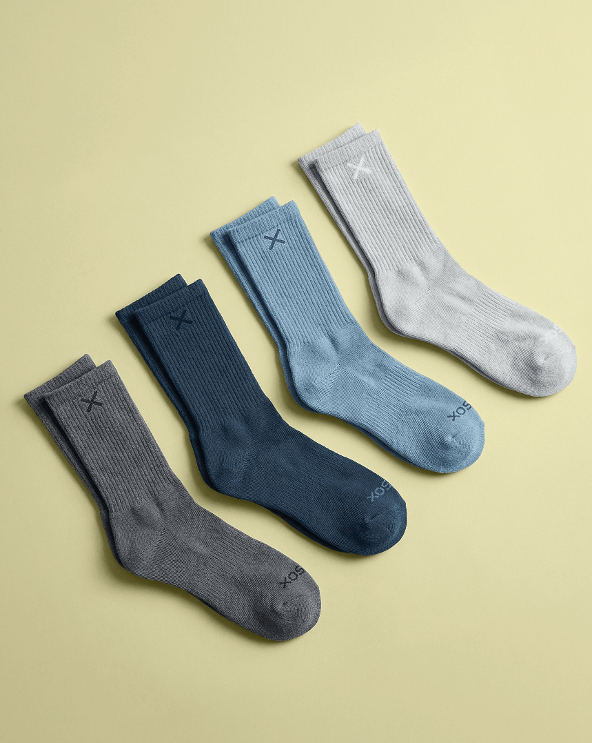 Four pairs of socks in gray, blue, and navy on a beige background
