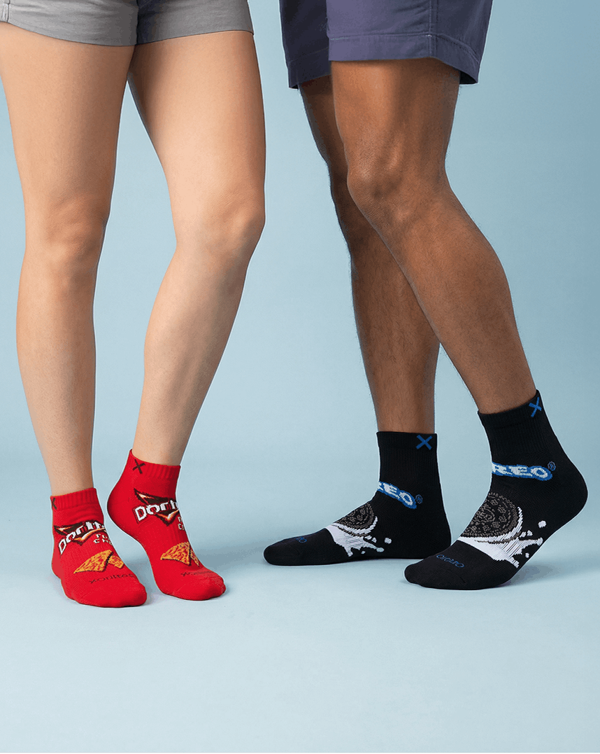 Two pairs of socks, one red and one black with designs, worn by two people on a light blue background.
