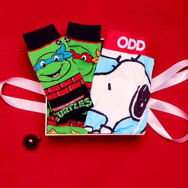 Two pairs of socks, one with a cartoon turtle design and the other with a dog wearing a helmet, on a red background.