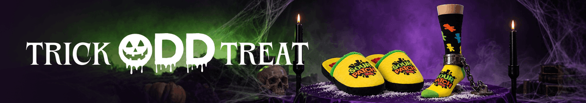 Halloween-themed promotional banner with the text 'TRICK ODD TREAT' in white dripping letters, a jack-o'-lantern face cutout, and three colorful novelty socks displayed on a purple cobwebbed surface with candles.