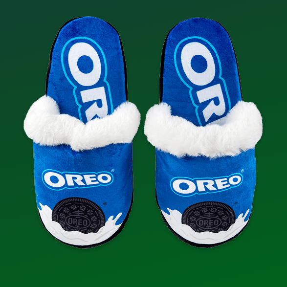 Blue Oreo slippers with white fur trim on a green background