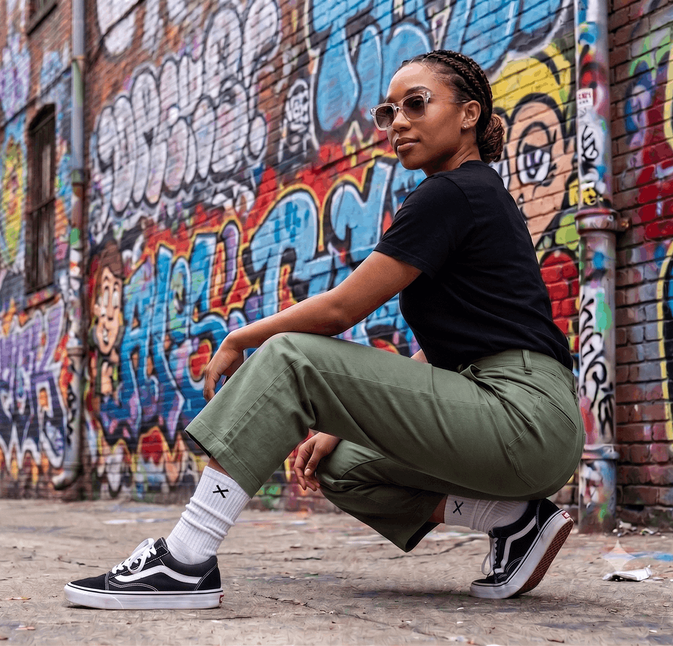 Person squatting in front of a graffiti-covered wall