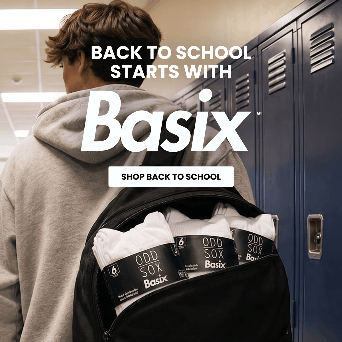 A person seen from behind wearing a gray hoodie and carrying a black backpack with white Basix Odd Sox underwear packs visible in the front pocket, standing in front of blue school lockers. Large text reads 'BACK TO SCHOOL STARTS WITH Basix' and 'SHOP BACK TO SCHOOL'.