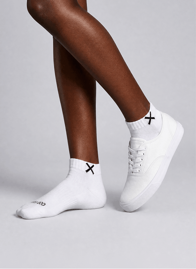 White sneakers and socks with black X design on a gray background
