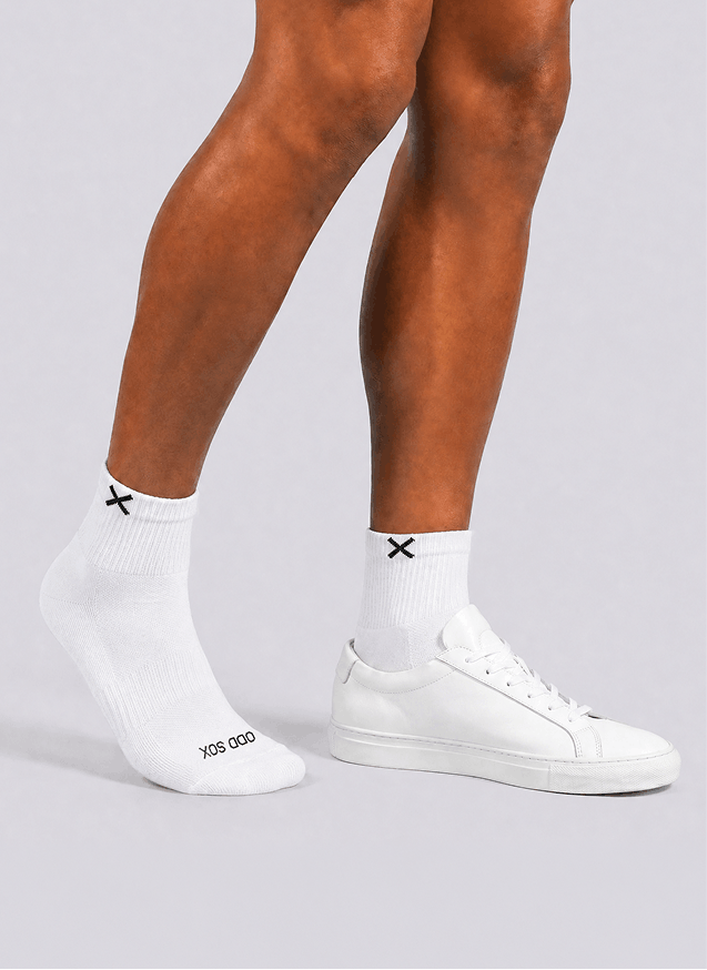 White socks with black x design worn by a person on a light gray background
