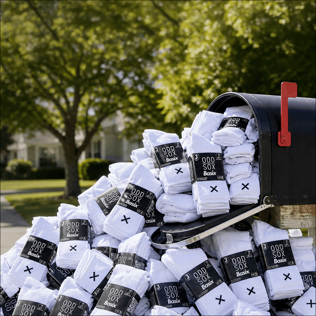 Pile of white socks with 'Odd Sox Box' labels in front of a mailbox outdoors.