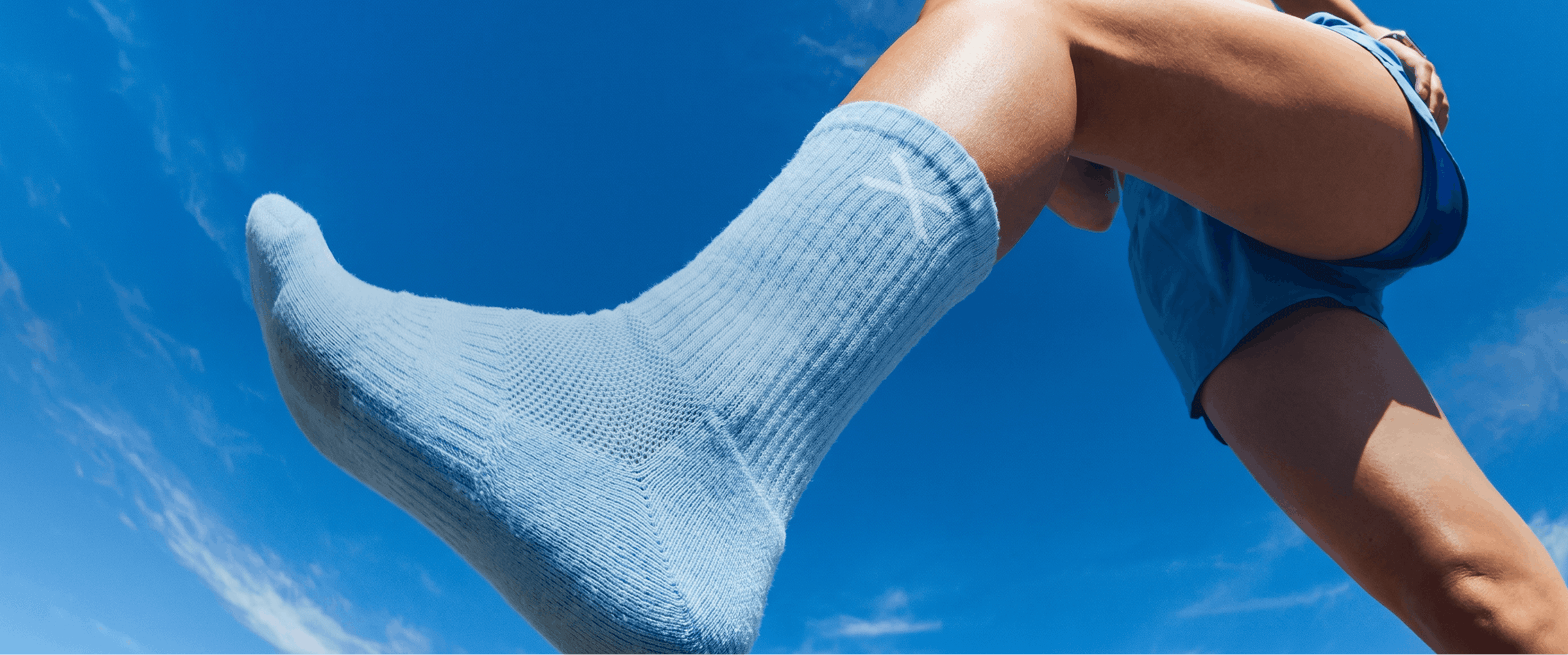 Person wearing light blue socks and shorts against a clear blue sky