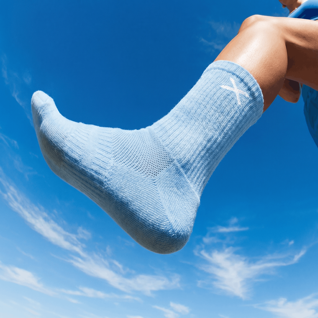 Light blue sock with a brand logo against a clear blue sky